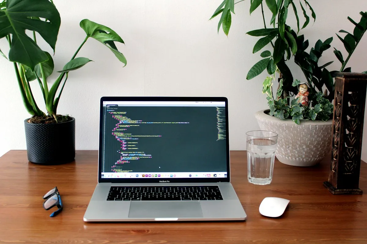 Laptop displaying code on a wooden desk with plants